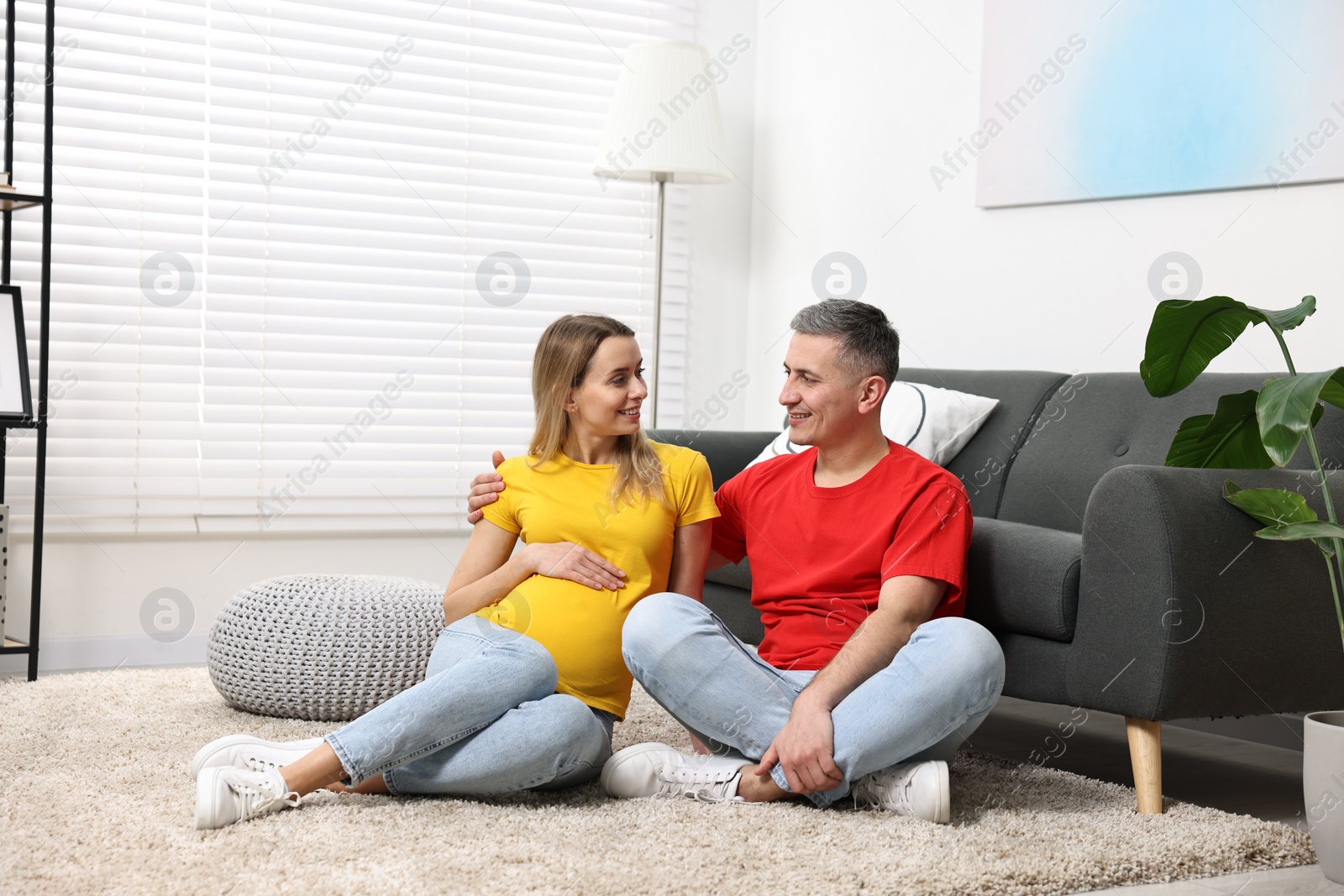 Photo of Young family housing concept. Pregnant woman with her husband on floor at home