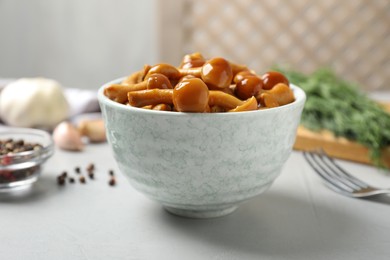 Tasty marinated mushrooms in bowl on grey table, closeup