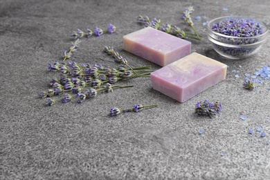Hand made soap bars with lavender flowers on grey stone table, space for text