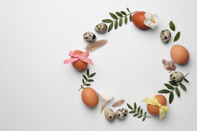 Photo of Frame of Easter eggs, twigs and flowers on white background. Space for text