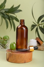Photo of Glass bottle of serum and olives on green background