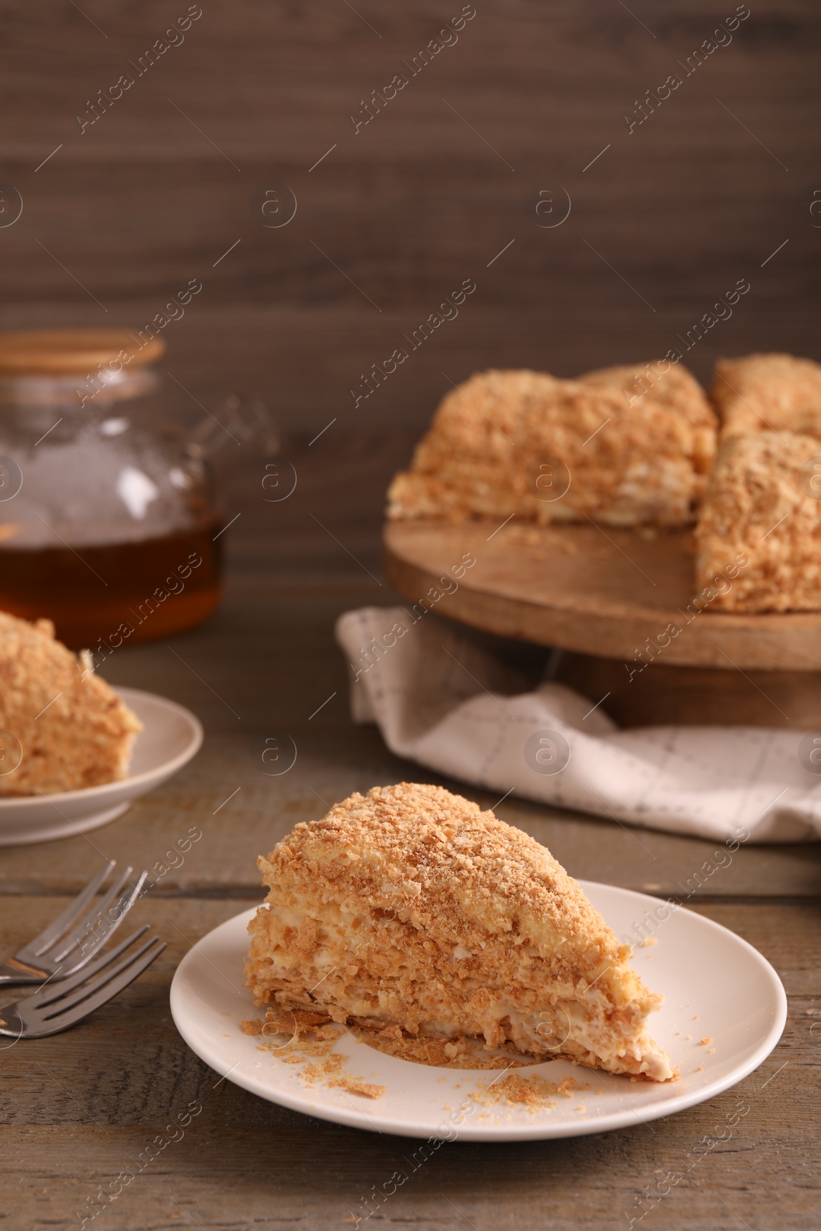 Photo of Piece of delicious Napoleon cake served on wooden table, closeup