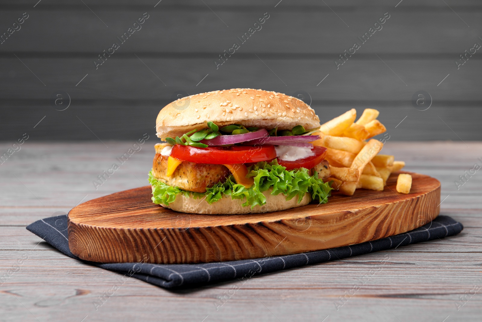 Photo of Delicious tofu burger served with french fries on grey wooden table