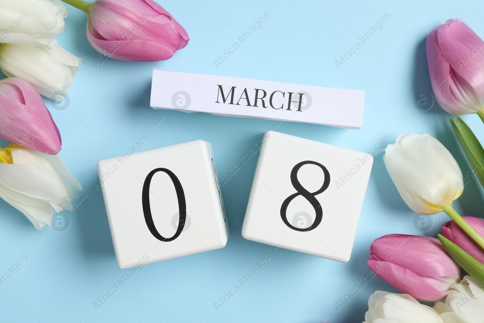 Photo of International Women's day - 8th of March. Block calendar and beautiful tulips on light blue background, flat lay