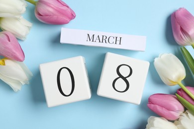 International Women's day - 8th of March. Block calendar and beautiful tulips on light blue background, flat lay