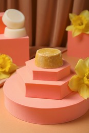 Photo of Stylish presentation of dry shampoo bars and daffodil flowers on light brown table