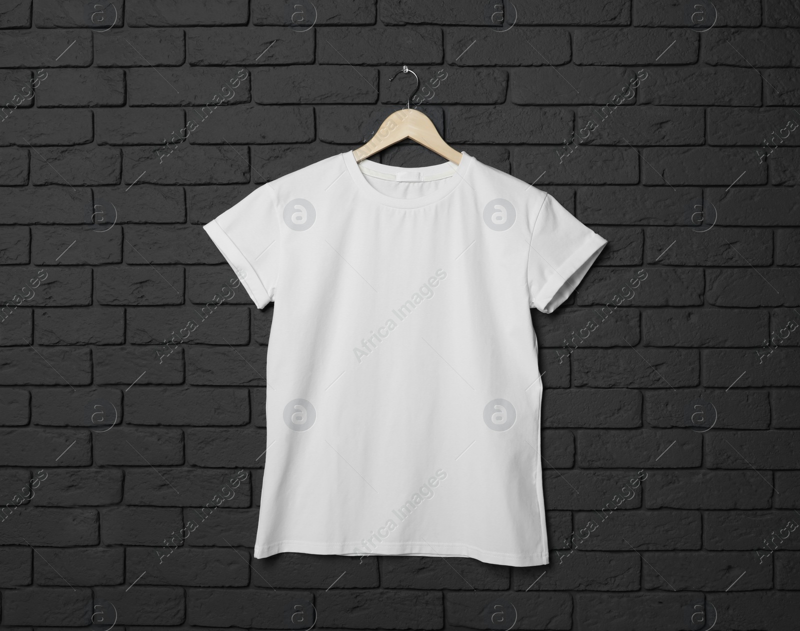 Photo of Hanger with stylish white T-shirt on black brick wall