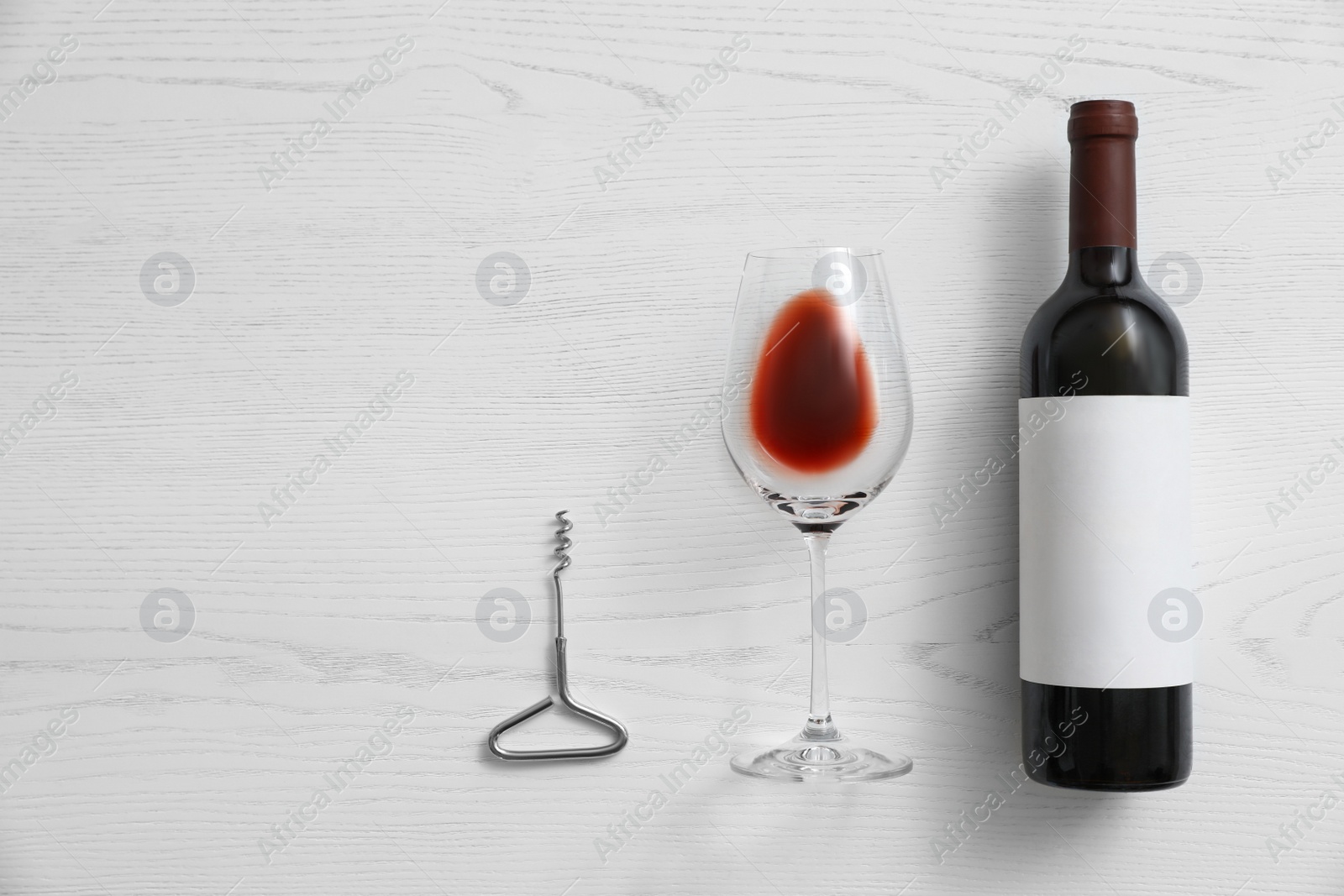 Photo of Flat lay composition with bottle of wine and elegant glass on white wooden background. Space for text