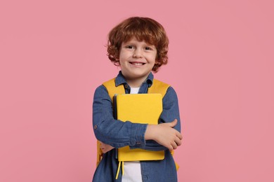Photo of Happy schoolboy with backpack and books on pink background