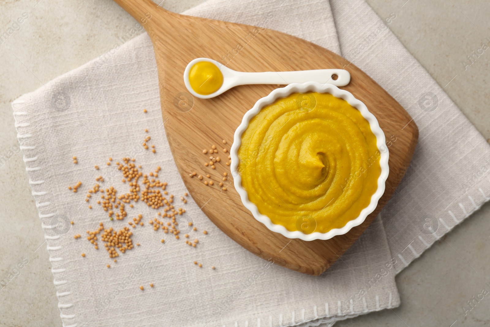 Photo of Tasty mustard sauce and dry seeds on light textured table, flat lay