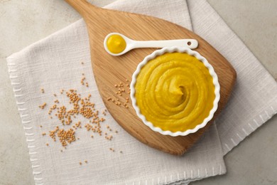 Tasty mustard sauce and dry seeds on light textured table, flat lay