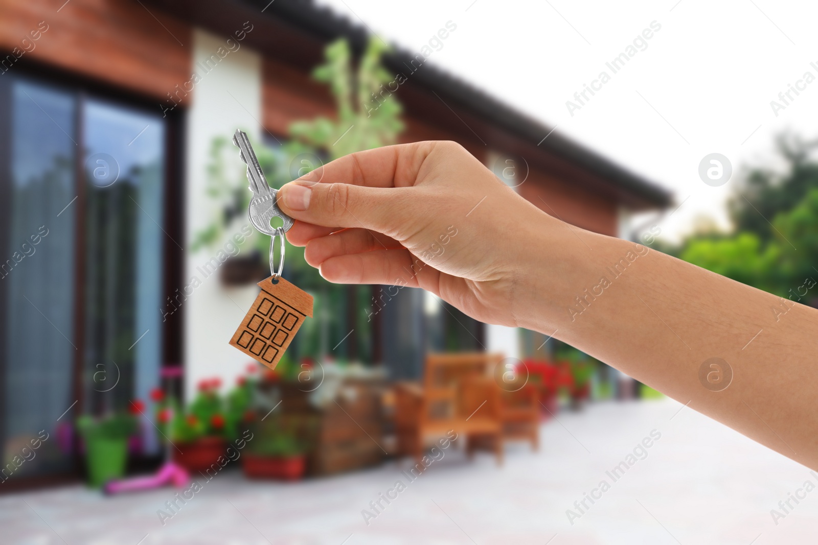 Image of Real estate agent holding key against modern house, closeup