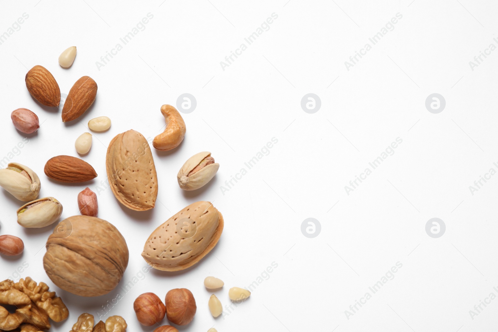 Photo of Different delicious nuts on white background, flat lay. Space for text