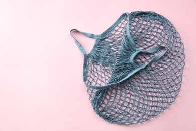 Blue string bag on pink background, top view. Space for text