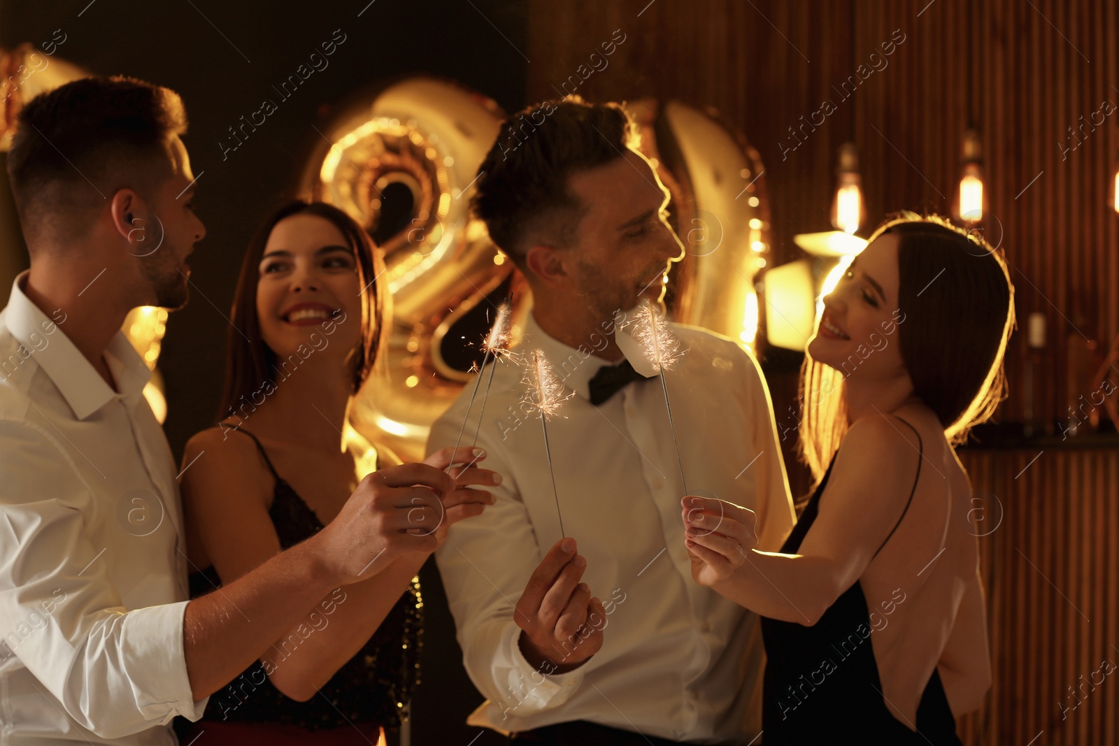 Photo of Young people celebrating New Year in club. Golden 2020 balloons on background