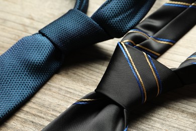 Photo of Two neckties on light wooden table, closeup
