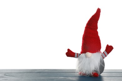 Photo of Funny Christmas gnome on blue wooden table against white background. Space for text