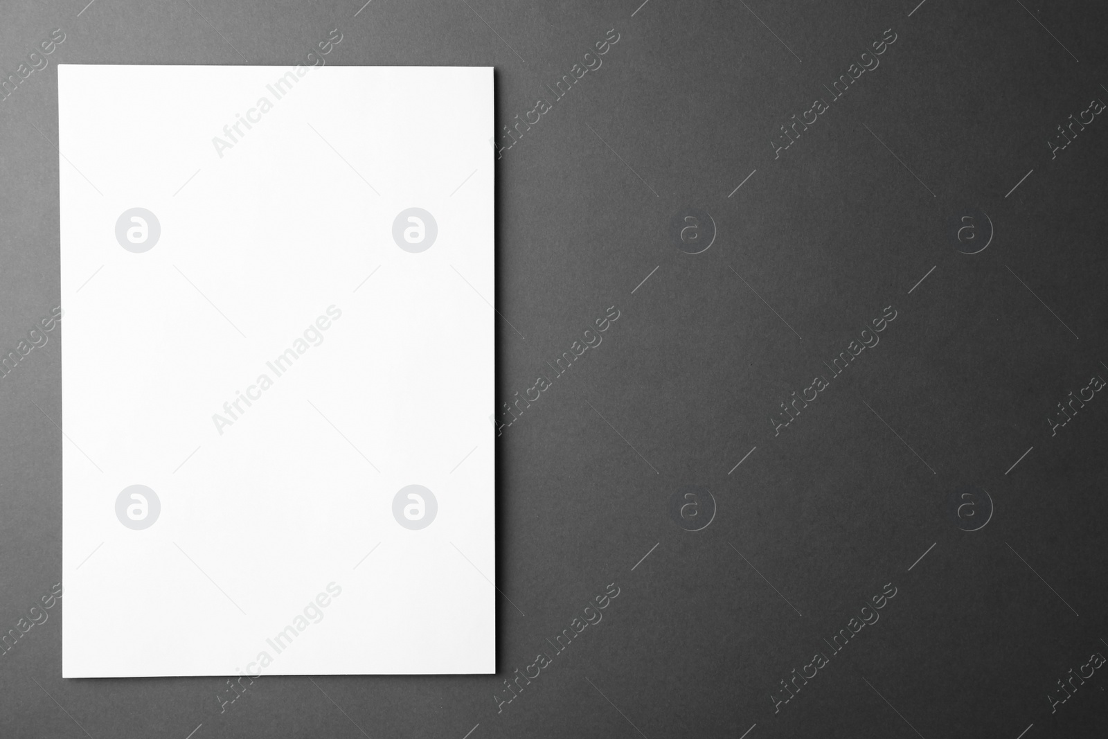 Photo of Blank paper sheet on dark grey background, top view. Mock up for design