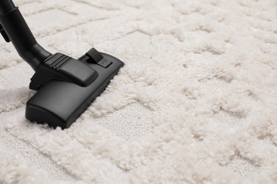 Photo of Hoovering carpet with modern vacuum cleaner, closeup. Space for text