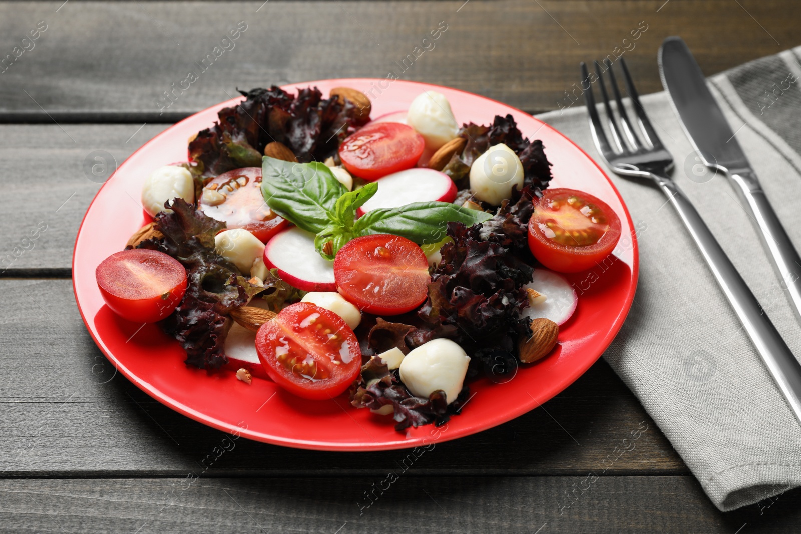 Photo of Delicious vegetable salad with mozzarella served on wooden table