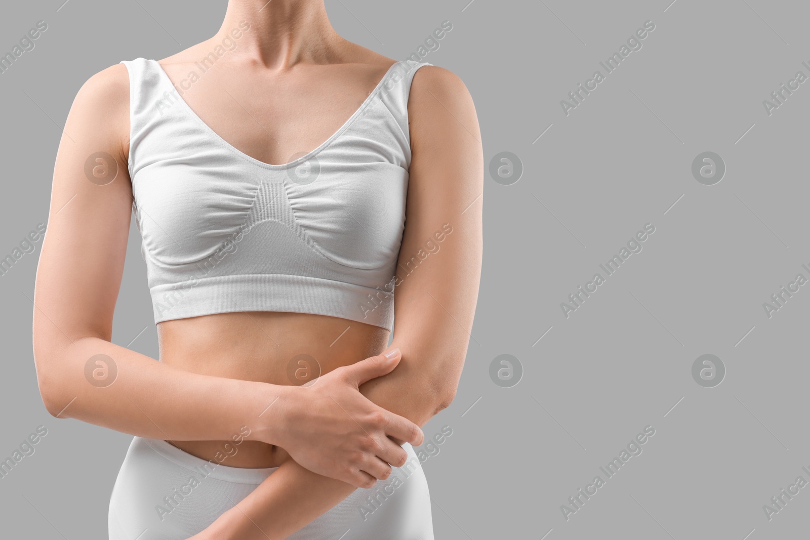 Photo of Sporty woman on grey background, closeup. Space for text