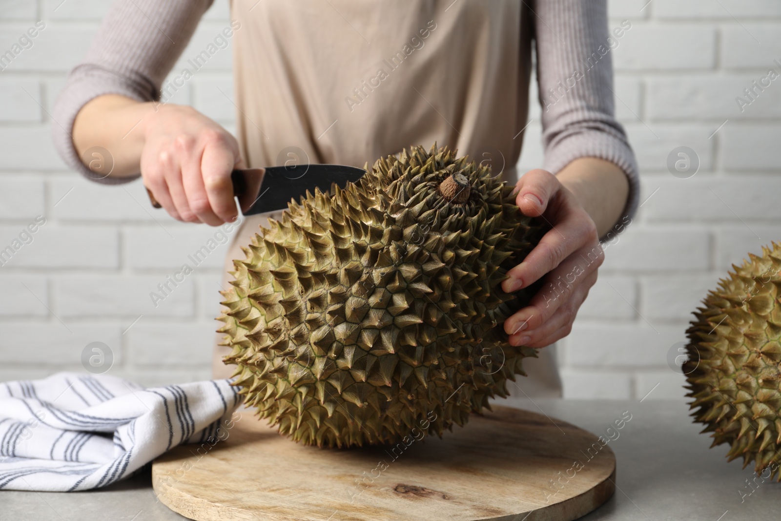 Photo of Woman cutting fresh ripe durian at table, closeup