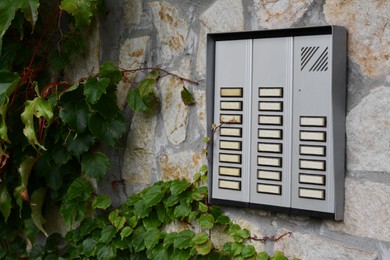 Photo of Modern intercom on concrete wall with stone fragments