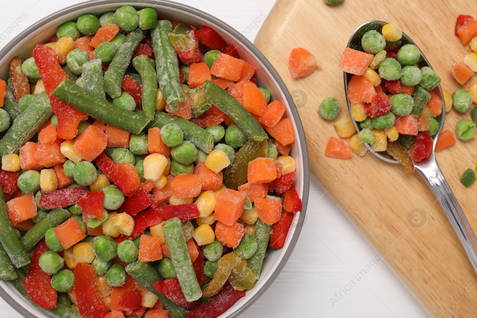 Photo of Mix of different frozen vegetables in bowl on white wooden table, top view