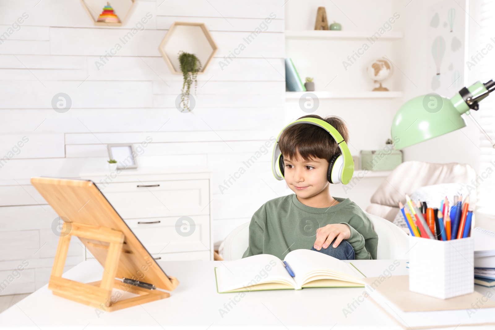 Photo of Cute little boy with modern tablet studying online at home. E-learning