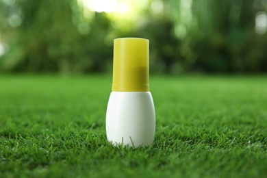 Photo of Bottle of insect repellent spray on green grass