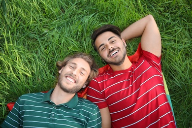 Photo of Happy gay couple lying on green grass, above view