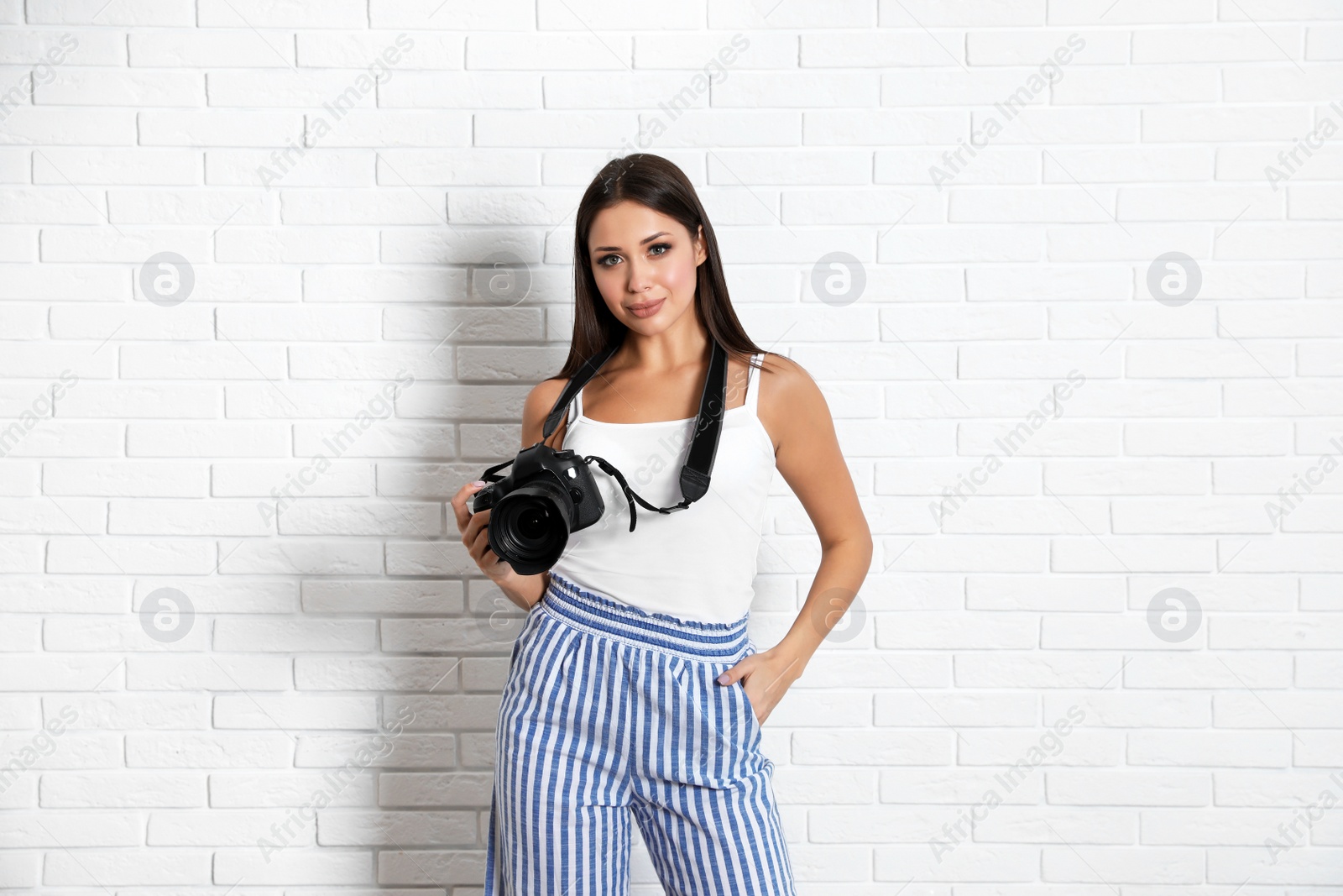 Photo of Professional photographer working near white brick wall in studio