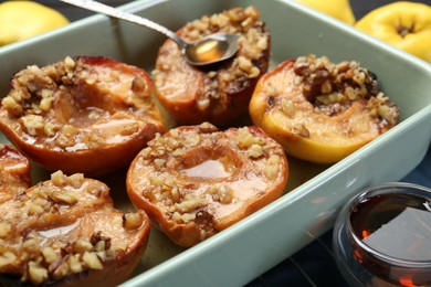 Photo of Tasty baked quinces with nuts and honey in dish on grid, closeup