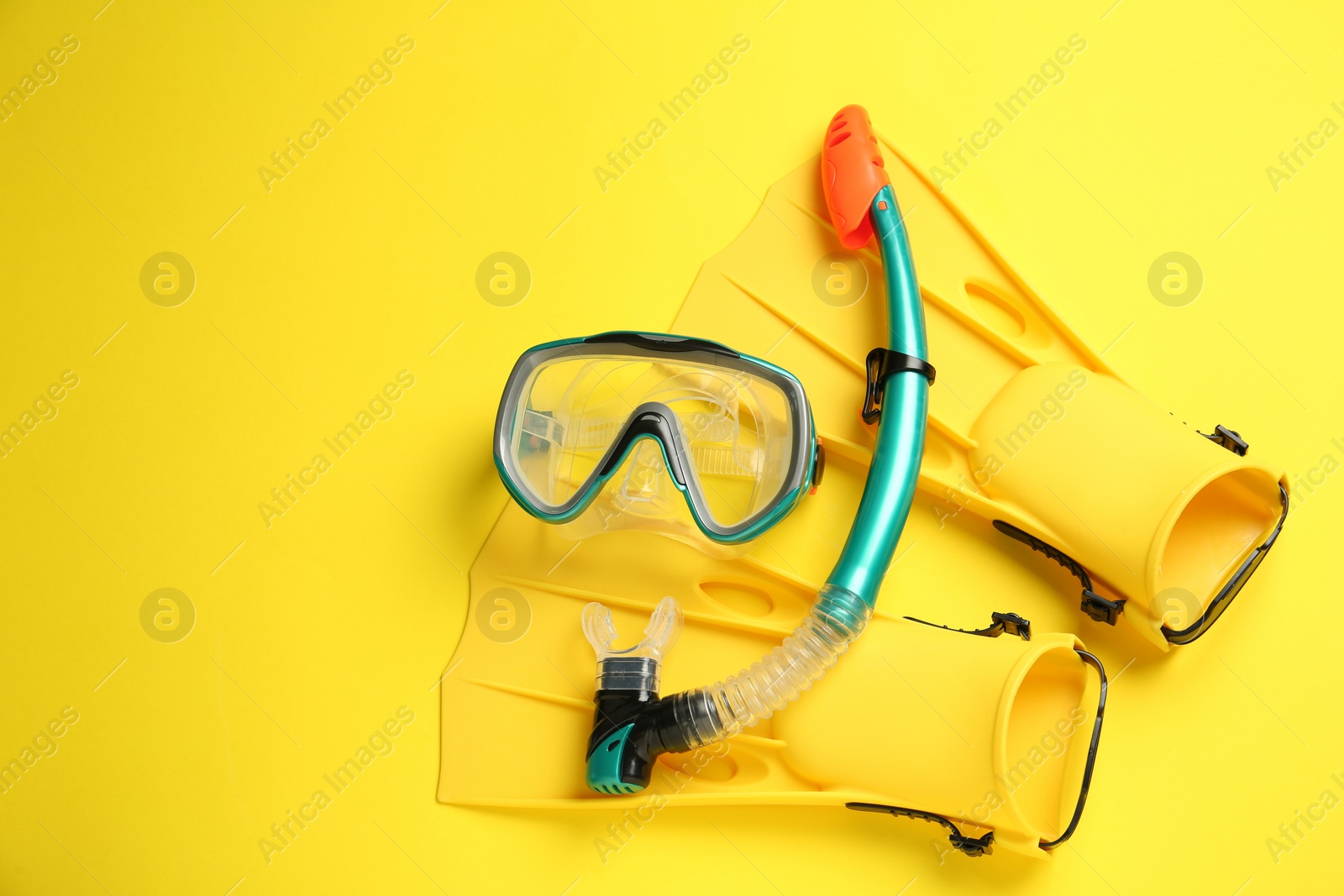 Photo of Pair of flippers and mask on yellow background, flat lay. Space for text