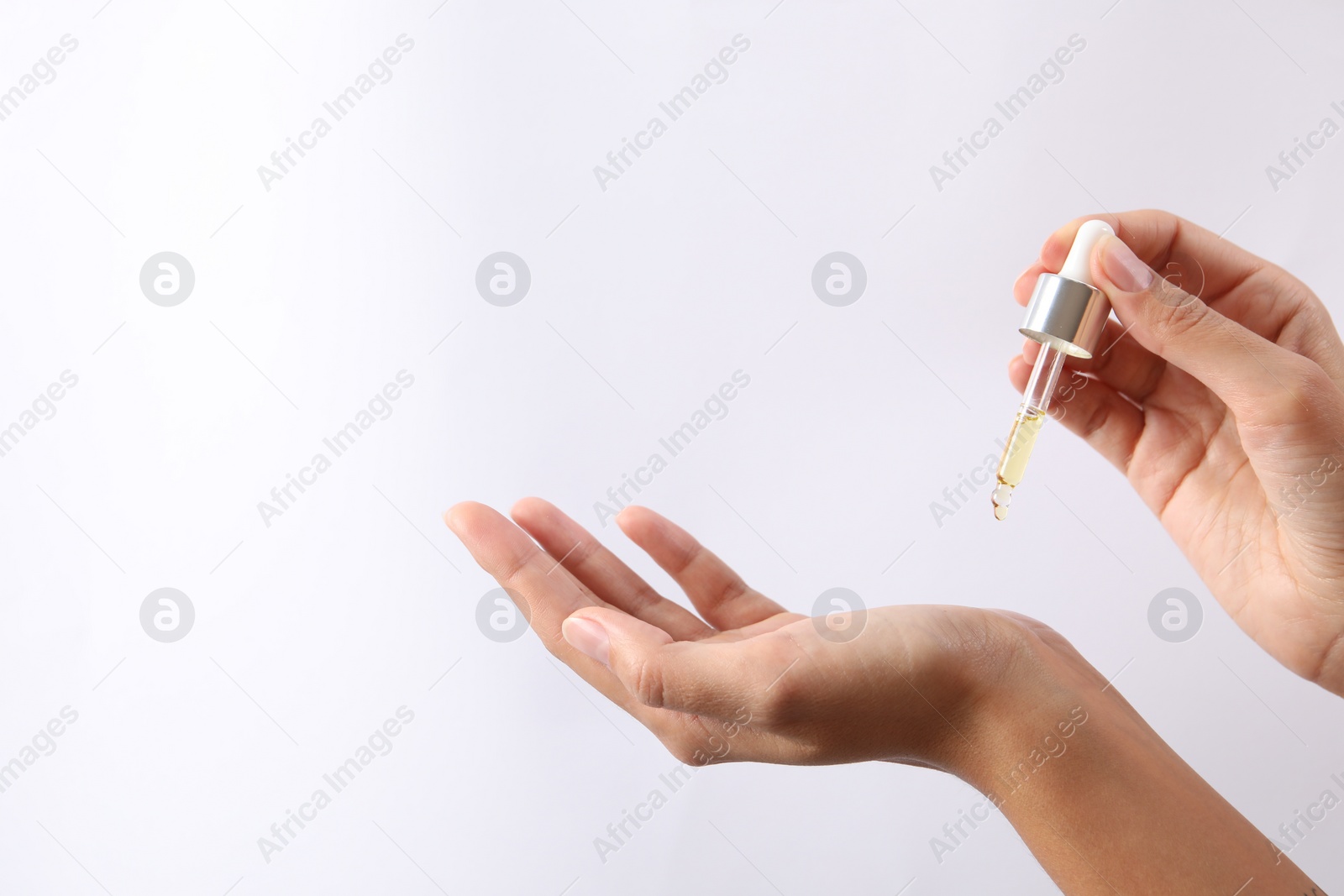 Photo of Woman applying cosmetic serum onto her hand on white background, closeup. Space for text