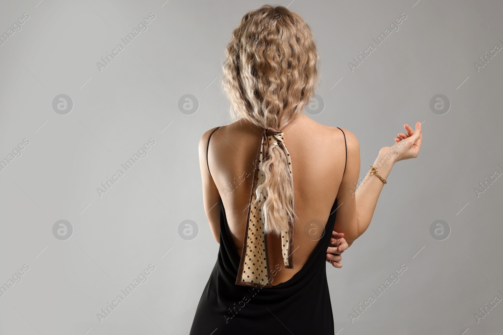 Photo of Woman with stylish bandana on light grey background, back view