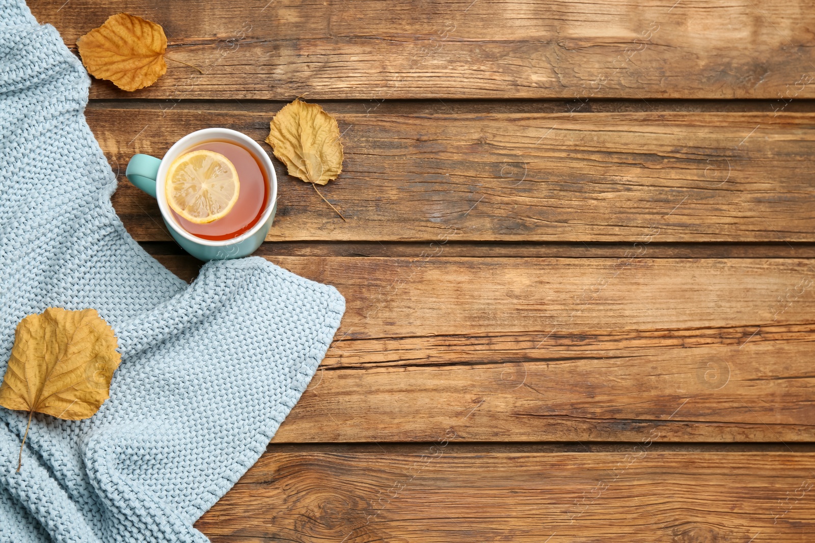 Photo of Flat lay composition with tea and warm plaid on wooden table, space for text