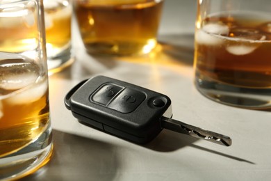 Photo of Car key near glasses of alcohol on table. Dangerous drinking and driving