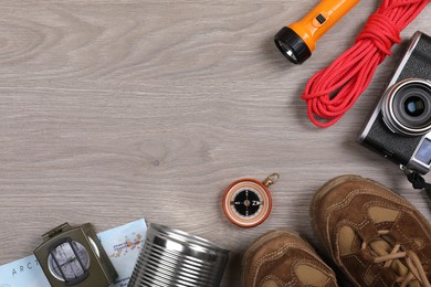 Photo of Flat lay composition with different camping equipment on wooden background, space for text