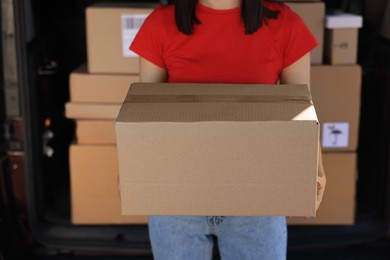 Courier with parcel near delivery van outdoors, closeup