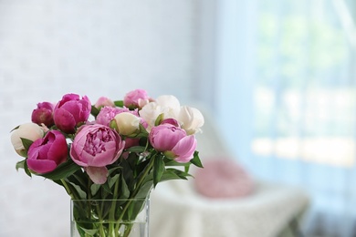 Photo of Vase with bouquet of beautiful peonies in room, space for text