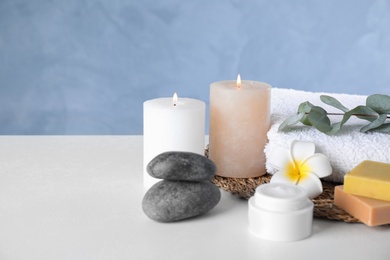 Photo of Composition with cream and burning candles on white table. Spa treatment