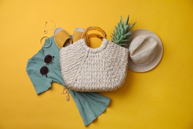 Stylish straw bag and summer accessories on yellow background, flat lay