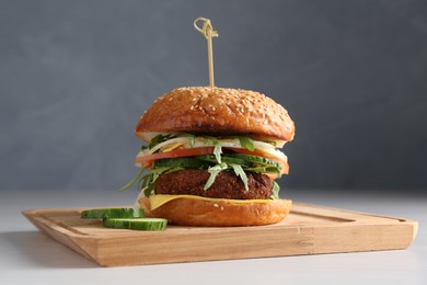 Photo of Board with delicious vegetarian burger on white table