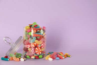 Photo of Jar with different delicious candies on violet background, space for text