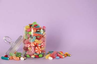 Jar with different delicious candies on violet background, space for text