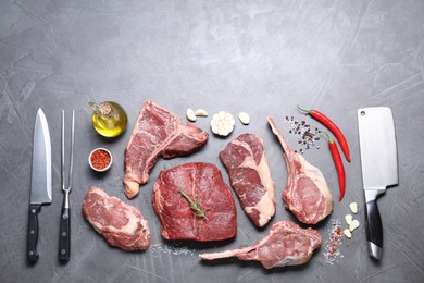 Fresh raw beef cuts, spices and butcher tools on light grey textured table, flat lay. Space for text