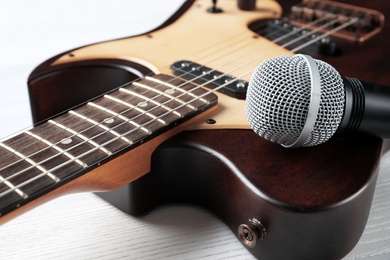 Modern electric guitar with microphone on wooden background, closeup view