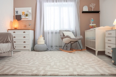 Cozy baby room interior with crib and rocking chair