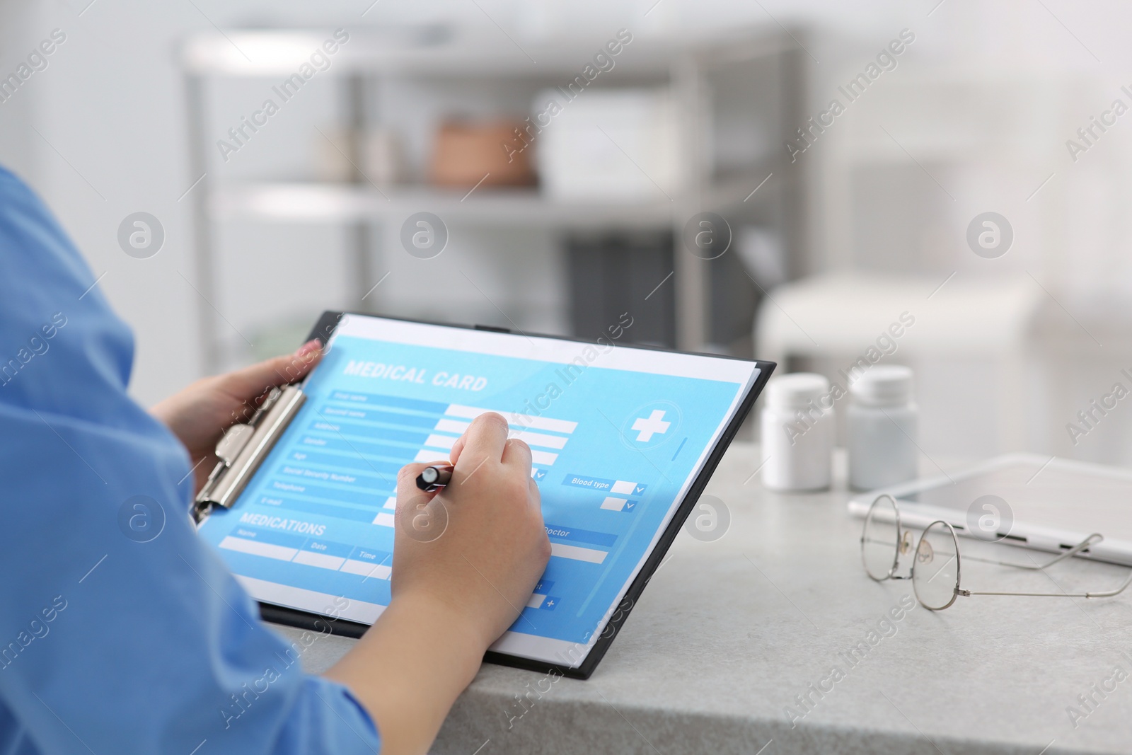 Photo of Doctor filling patient's medical card in clinic, closeup